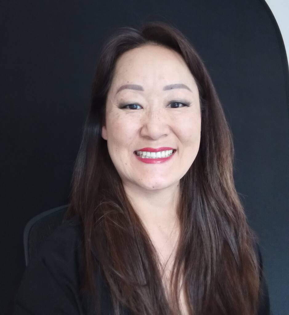 A woman with long straight hair smiles into the camera