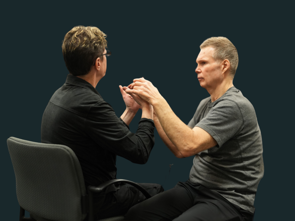 Two people communicating in tactile sign language and touching hands.