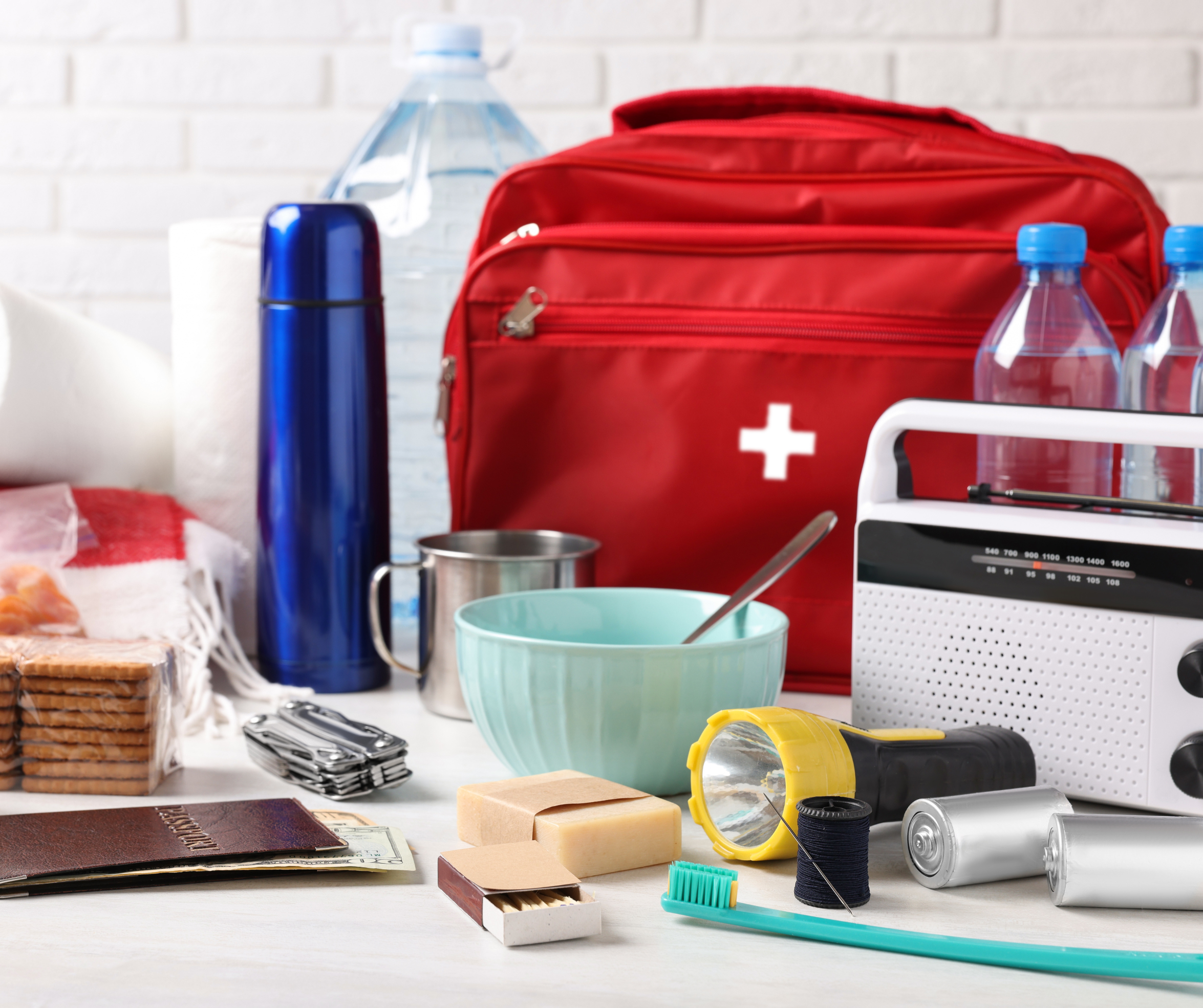 Several items for an emergency kit such as water bottles, food, a flashlight, batteries, a first aid kit, and more.