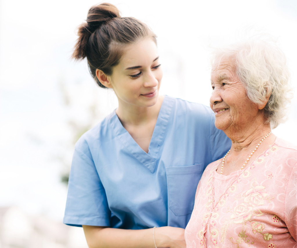 A woman smiles and stands close to an older woman who also smiles.