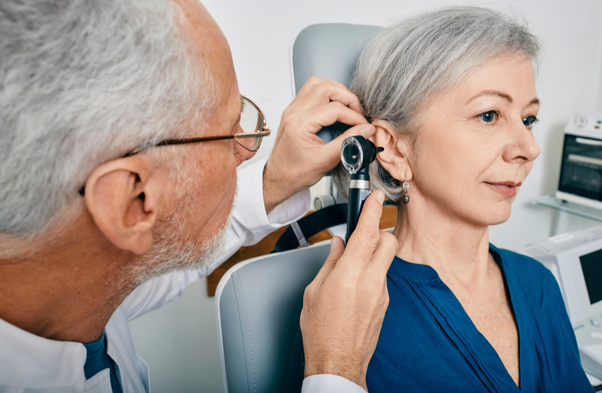 A doctor examining a middle aged woman's ear.