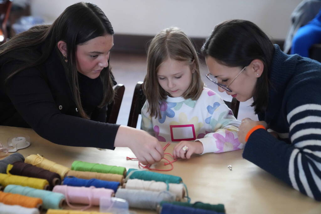 A teen and adult help a child engage in a tactile arts & craft project.