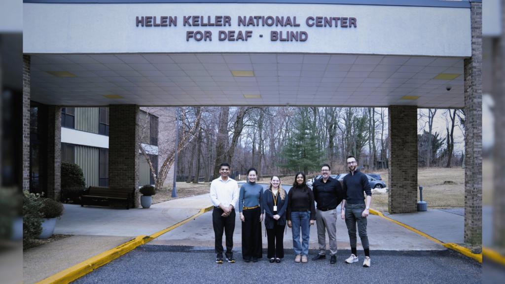 Johns Hopkins Researchers, HKNC staff member, and the HKNC Executive Director pose for a photo under the Helen Keller National Center sign.